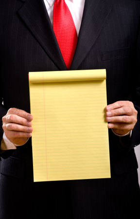 A business man in a blue suit and a red necktie holding a yellow tablet add your own copy or text, business communicationsの写真素材