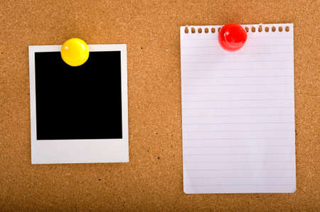 A photograph and a note on a corkbaord or bulletin board, held with oversized colorful push-pinsの写真素材