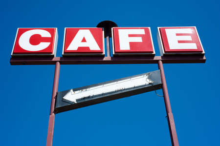 A red and white Cafe sign on a brighty blue sky backgroundの写真素材