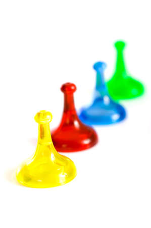 A row of colorful generic game pieces on a white background, focus is on the yellow game piece in the foregroundの写真素材
