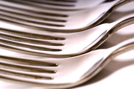 A background of a row of white dinner forks on a white backgroundの写真素材