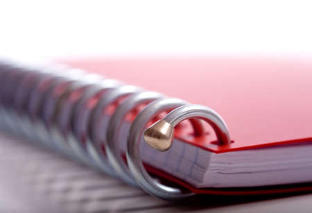 A spriral notebook background, very shallow depth of field, focus in on the gold tip on the end of the spiral notebook and blurs quicklyの写真素材