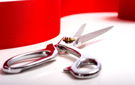 A red ribbon with a pair or shiny silver ceremonial scissors or sheers