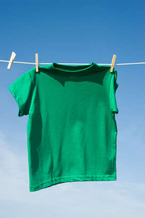 Individual t-shirts on a clothesline in front of a beautiful blue sky.  Add text or graphics to shirts, copy spaceの写真素材