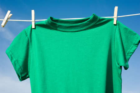 Individual t-shirts on a clothesline in front of a beautiful blue sky.  Add text or graphics to shirts, copy spaceの写真素材