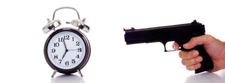 A black vintage looking Alarm clock with a personor man holding a gun to it.  Stressed by timeの写真素材