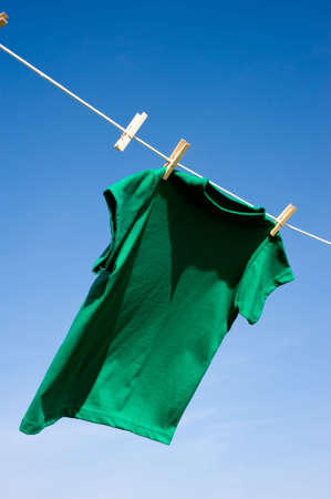 A green colored T-shirts hanging on a clothesline on a beautiful, sunny day, add text or graphic to shirts or copy spaceの写真素材