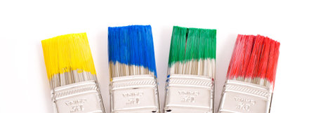 A row of primary colored paint brushes on white background with copy space