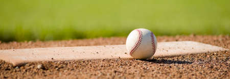 A white leather baseball lying on top of the pitcher's mound at a baseball field with copy spaceの写真素材