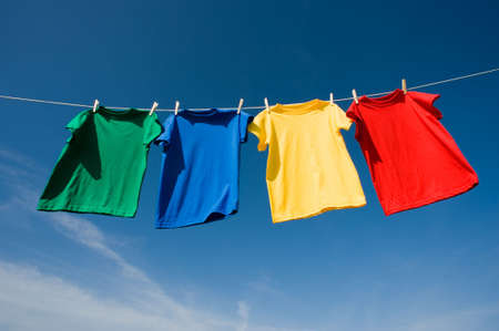 a set of primary colored T-shirts hanging on a clothesline on a beautiful, sunny day, add text or graphic to shirts or copy spaceの写真素材