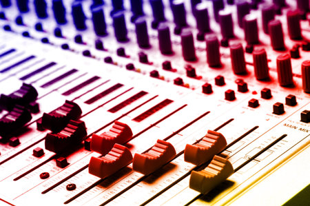 Audio recording equipment or soundboard background with many knobs and adjustments, board is a...