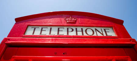 A red telephone booth from England in fron of a blue skyの写真素材