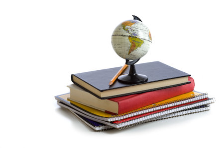 A stack of school books and notebooks with a miniature globe