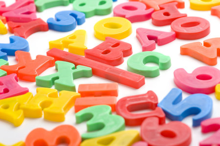 A group of colorful plastic alphabet letter magnets on a white background, focus is on the B in ABC.