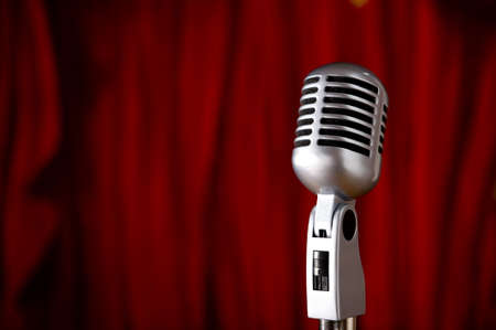 A silver vintage microphone in front of a red stage curtain with copy spaceの写真素材