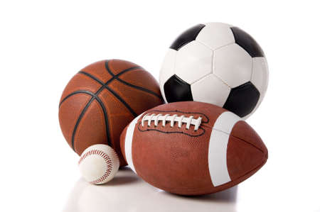 A group of sports balls on a white background, including a baseball, an American football, a basketball, and a soocer ballの写真素材