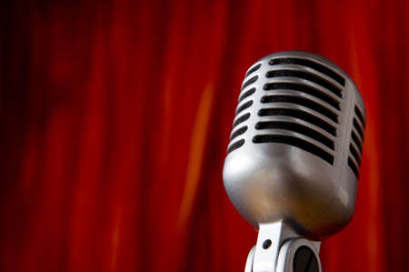 A silver vintage microphone in front of a red stage curtain with copy spaceの写真素材