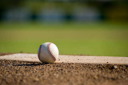 A white leather baseball lying on top of the pitcher's mound at a baseball field with copy spaceの写真素材