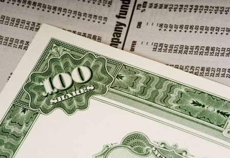 A stock certificate lying on top of the financial or business section of a newspaperの写真素材