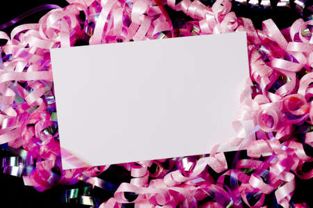A blank white notecard or note surrounded by curly ribbons or bows on black, Party Invitation or communicationの写真素材