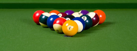 A game of pool with the balls lined up in an 8-ball formation on a green felt pool table