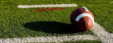 A brown leather American football on a green football field