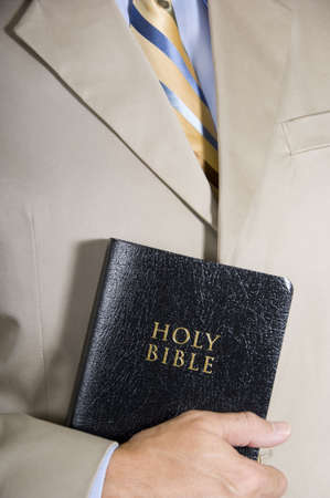 A business man or preacher in a business suit holidng a copy of the Holy BIbleの写真素材