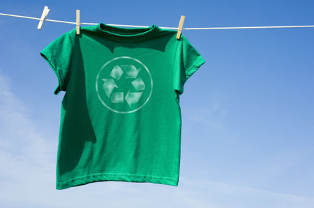 A green t-shirt hanging on a clothesline with the recycle symbol on the front,  environmental or recycling themeの写真素材