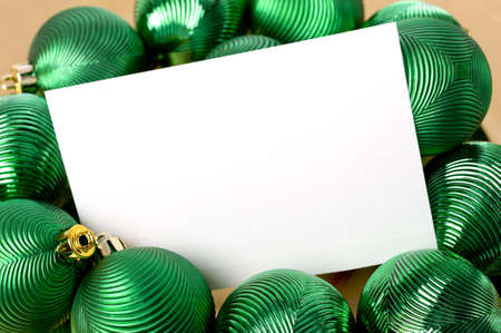A group of colorful Christmas baubles or ball surrounding a white notecard with copy spaceの写真素材