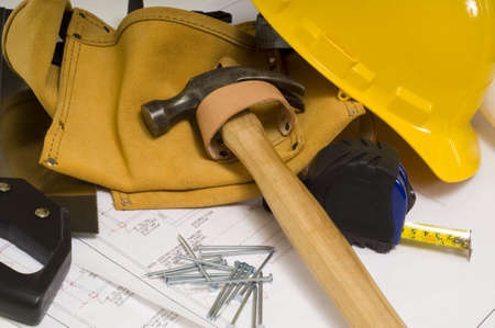 supplies of a construction worker or a handy man, including a hammer, tape measure, nails, tool belt and blue prints or plansの写真素材