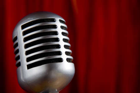 A silver vintage microphone in front of a red stage curtain with copy spaceの写真素材