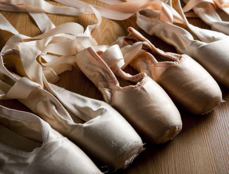 A group or background of used ballet pointe shoes or slippers on a wooden floorの写真素材
