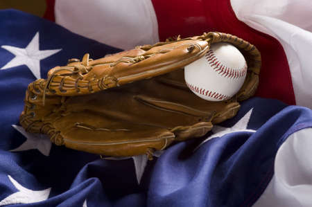 A baseball glove with a ball lying on top of an American Flag.の写真素材