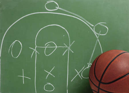 A leather basketball in front of a green chalkboard with a play or strategyの写真素材