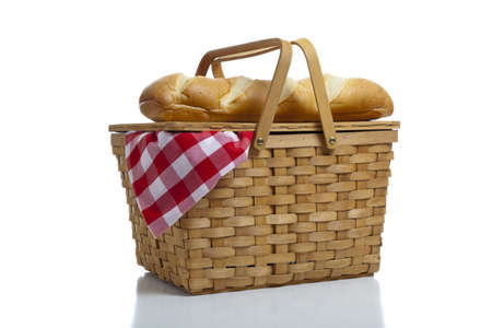A wicker picnic basket with a red gingham cloth and bread on a white backgroundの写真素材