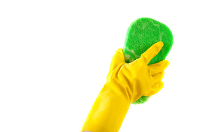 A gloved hand washing with a sponge a white surface with copy space
