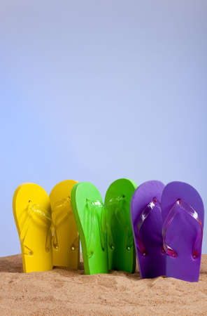 Four pairs of colorful flip-flop sandles on a beach background, studio shotの写真素材