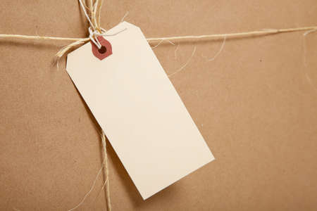 A brown shipping box tied with twine or string with a blank shipping label with copy spaceの写真素材