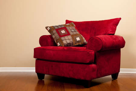 A modern red fabric oversized chair on hardwood flooring in a house with copy spaceの写真素材