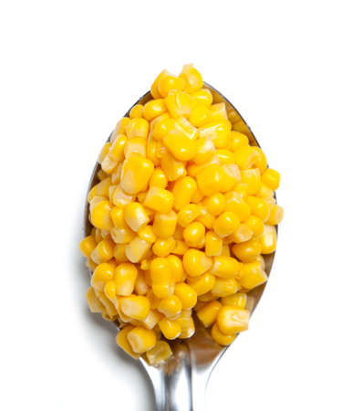 A spoon full of yellow corn on a white background - vegetablesの写真素材