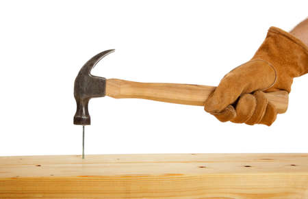 A leather gloved mans hand drivng a nail oon a white backgroundの写真素材