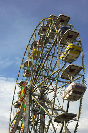 A large ferris wheel in front of a blue sky with multicolor carsの写真素材