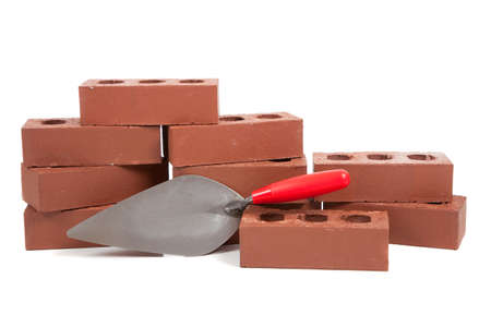 A stack of red bricks on a white background with a pointing trowelの写真素材
