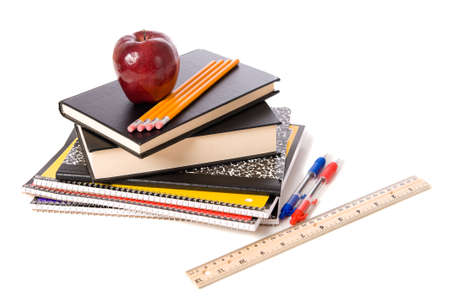 A group of assorted school supplies on a white background with books, pencils, a ruler, notebooks, and ann appleの写真素材