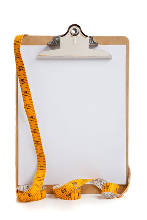 A blank clipboard with a yellow measuring tape with copy space on white backgroundの写真素材