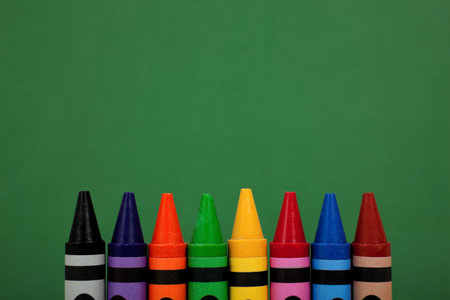 Assorted crayon tops with a green chalkboard background