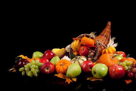 fall arrangement of fruits and vegetables in a cornucopia on a black backgroundの写真素材