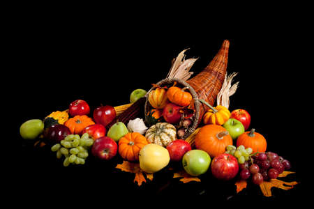 fall arrangement of fruits and vegetables in a cornucopia on a black backgroundの写真素材