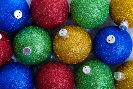 A background comprised of blue, green, red and gold glittery Christmas ornaments