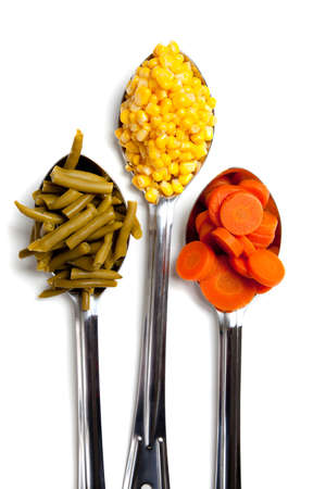 Spoonfuls of green beans, corn and carrots on a white backgroundの写真素材